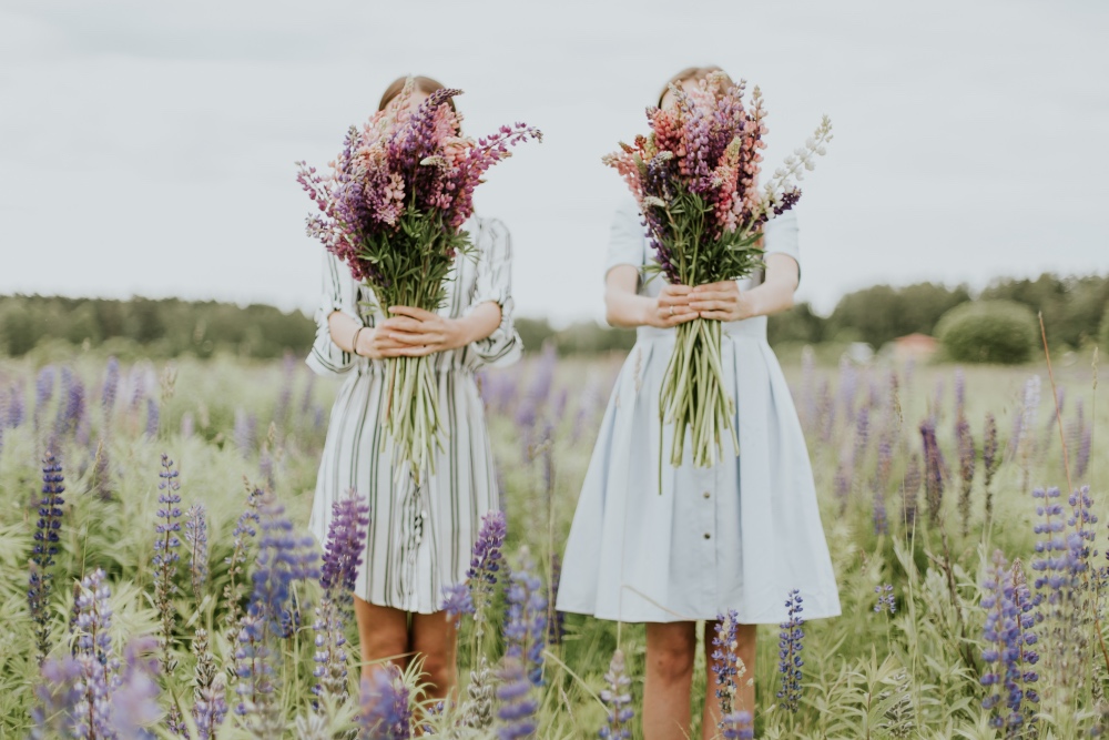 Zwei Mädchen stehen in einer Weise mit Lavendel und halten einen Strauß Blumen in der Hand