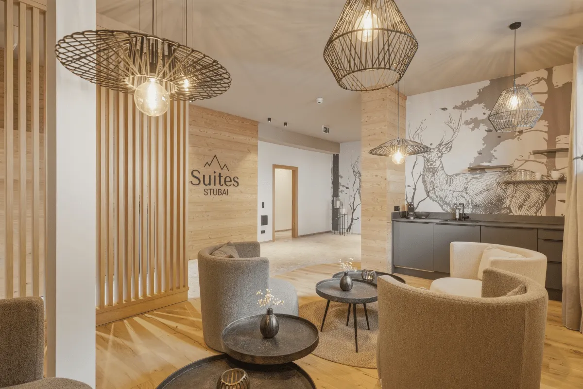 Lobby der Suites Stubai mit Holzlamellen, Korblampen und hellen Sesseln