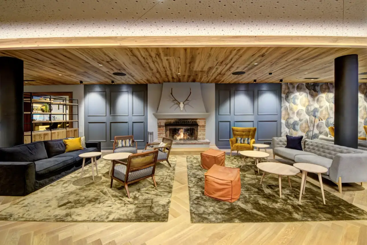Lobby im Hotel Gut Brandlhof mit offenem Kamin, Holzdecke und Sitzgruppen