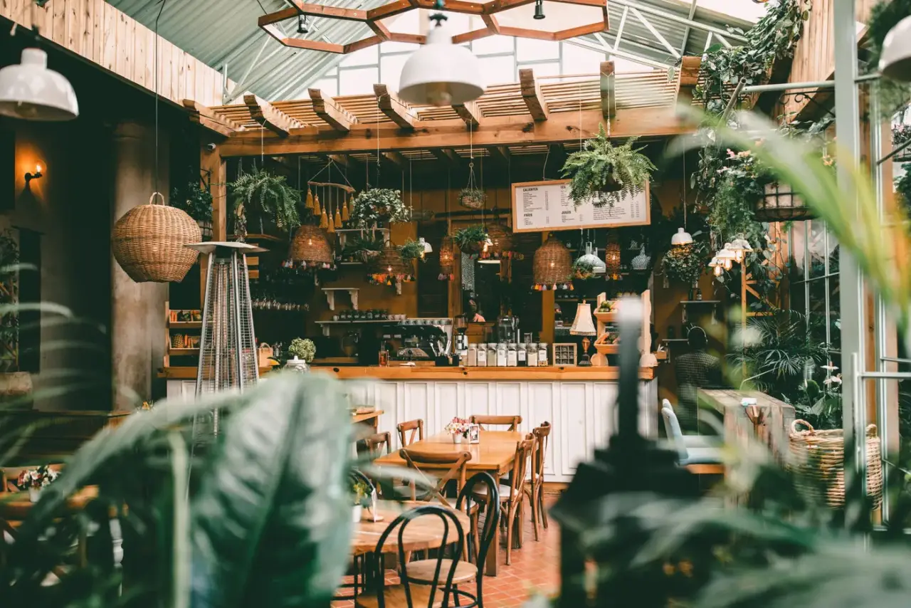 Bar mit Holzpergola, Hängelampen und vielen Grünpflanzen in einem Gastgarten