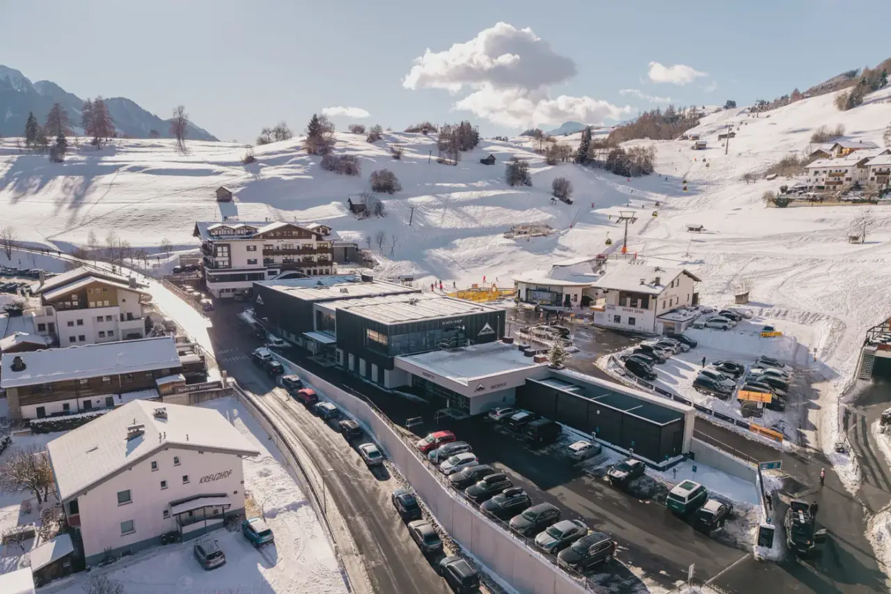Das neue Skidepot Ladis von oben: das dunkle Talstationsgebäude zwischen verschneiten Hängen, Hotels und dem Parkplatz