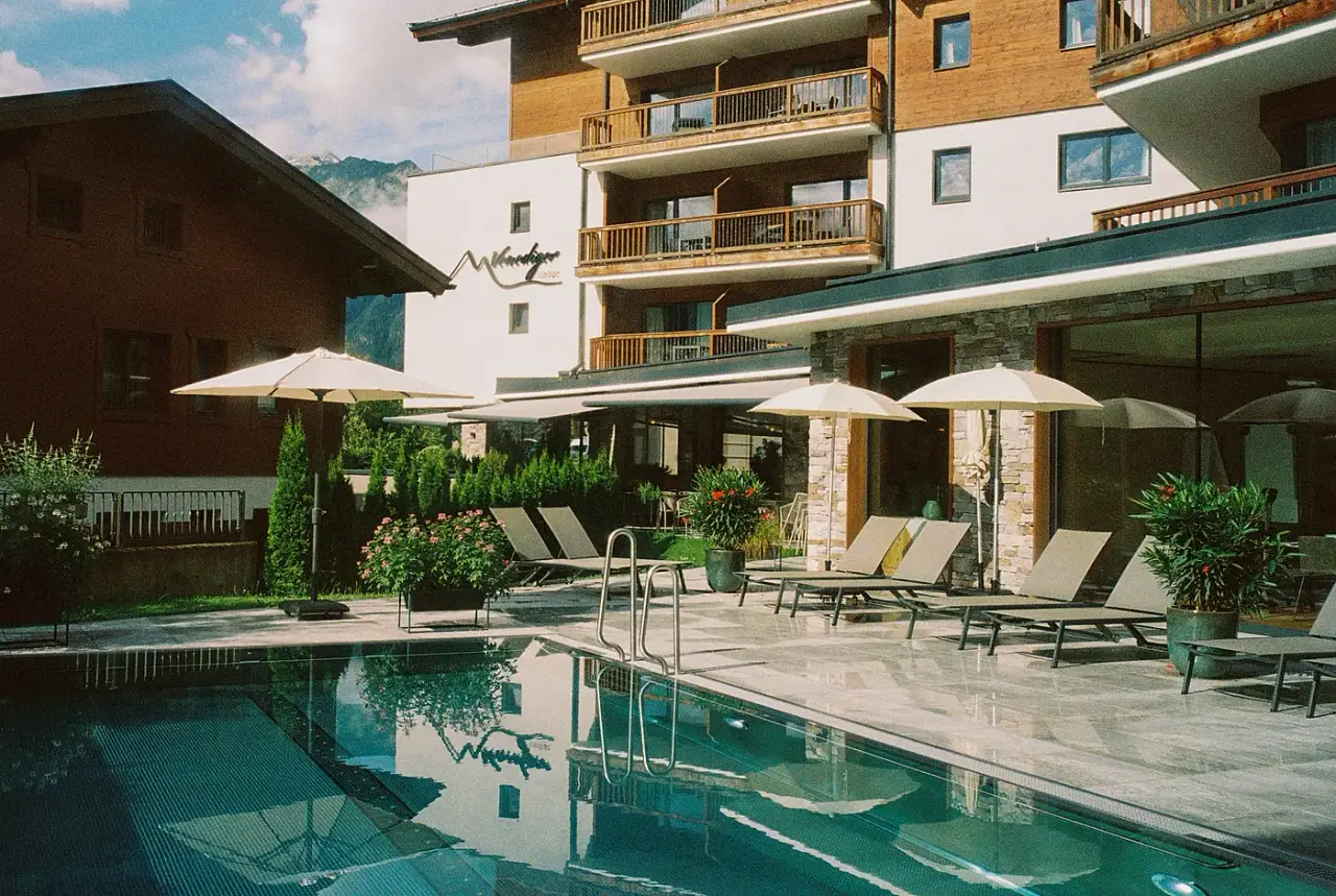Außenpool der Venediger Lodge mit Liegen und Sonnenschirmen vor der Bergkulisse